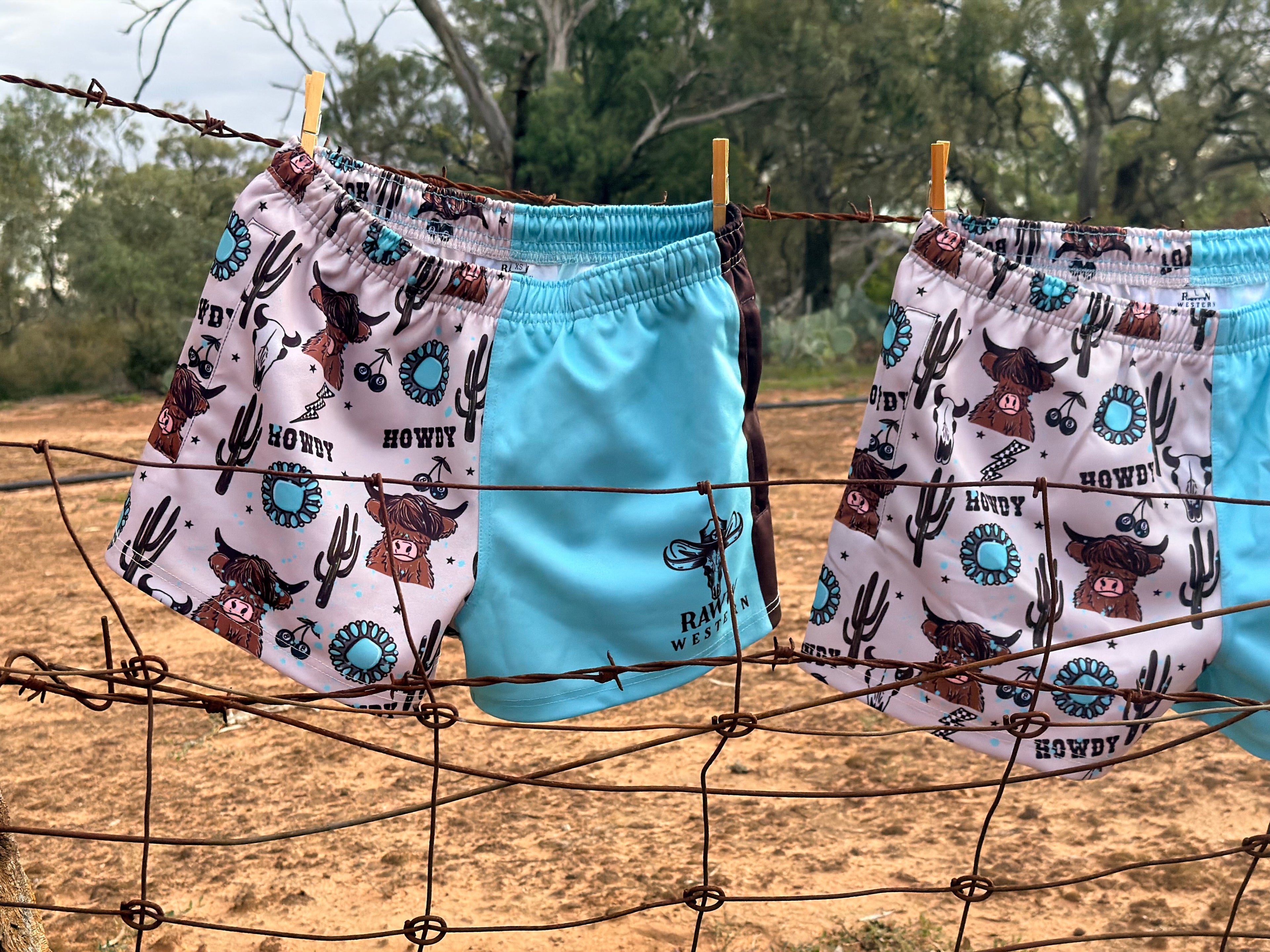 Footy shorts pair hanging: white cowboy print on one side and bright blue on the other