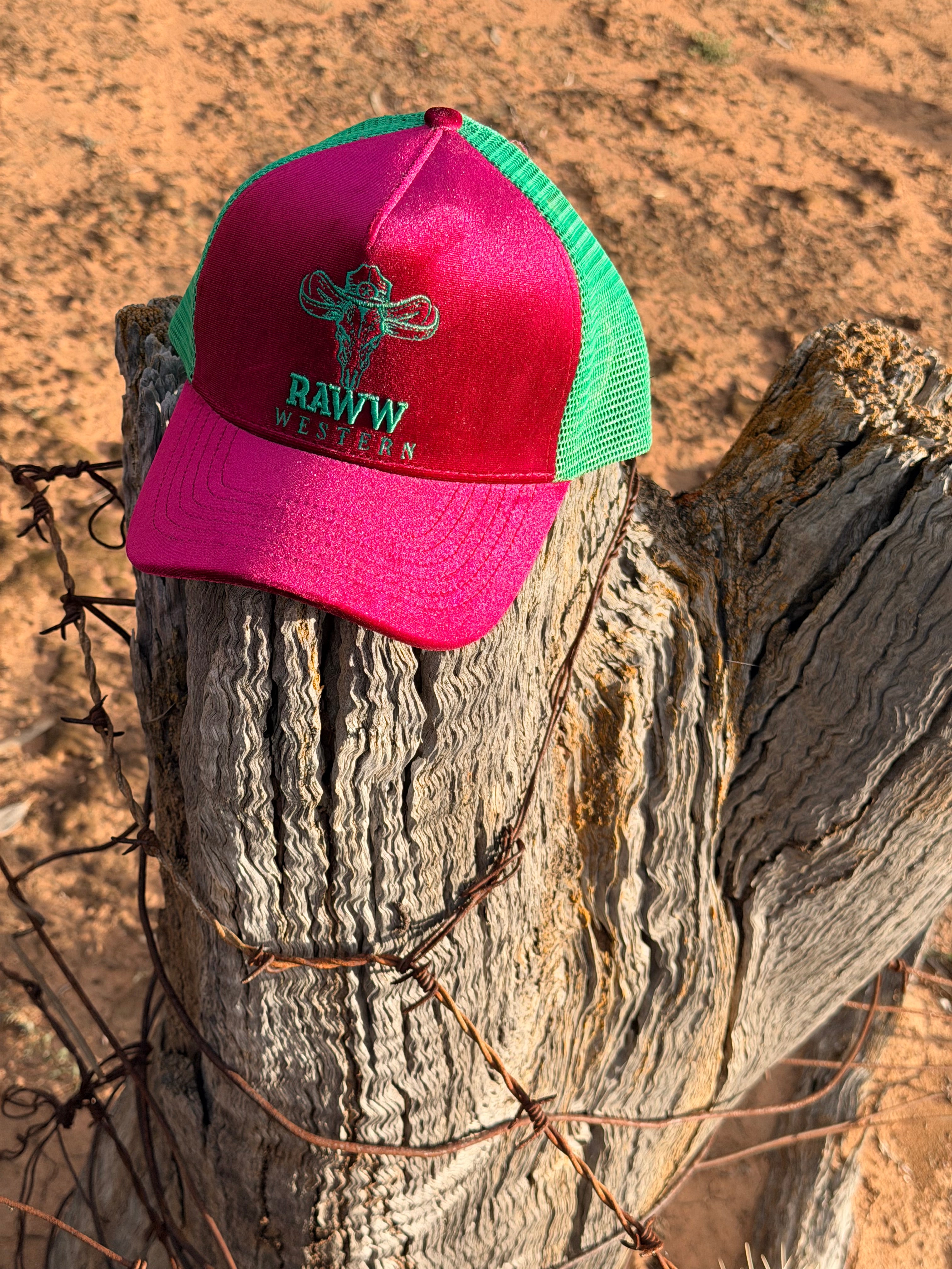 Ruby velvet trucker cap on a rustic post, green mesh back, RAW WES tern embroidery
