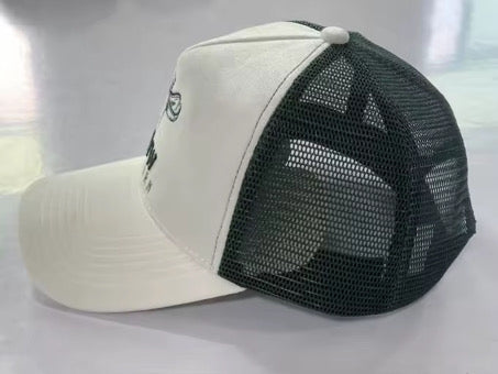 Trucker cap angled view: white front panels with dark green mesh sides and brim