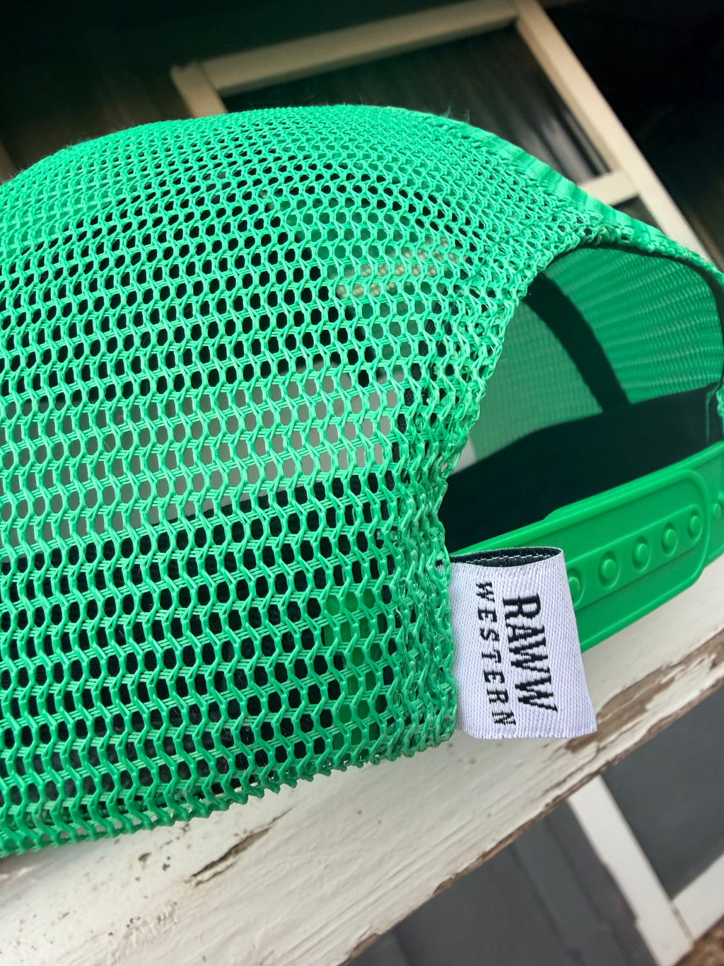 Green mesh back of ruby trucker cap with brand tag stitched inside