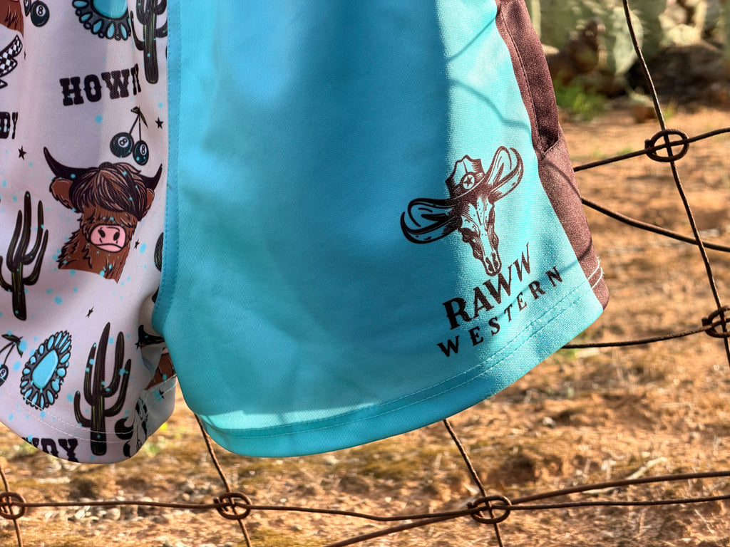 Footy shorts close-up: bright blue leg with RAW WESTERN bull graphic