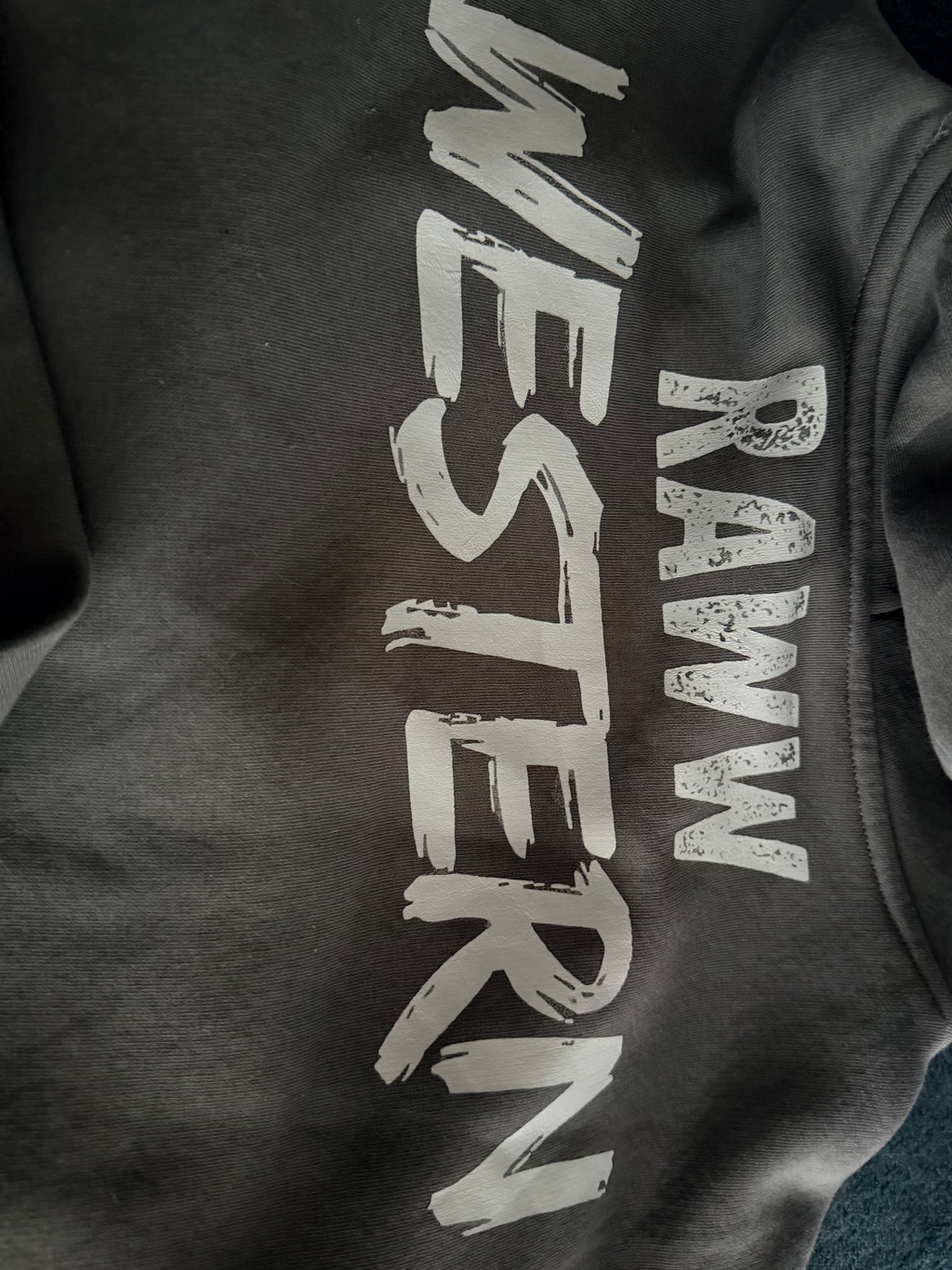 Faded grey hoodie close-up of large Raww Western-style logo print